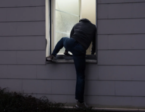 burglar trying to break into window with security window film