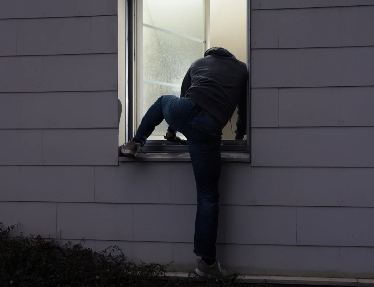 burglar trying to break into window with security window film